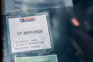 Détail d'une vignette de contrôle technique mentionnant la date de validité et le numéro de série du véhicule