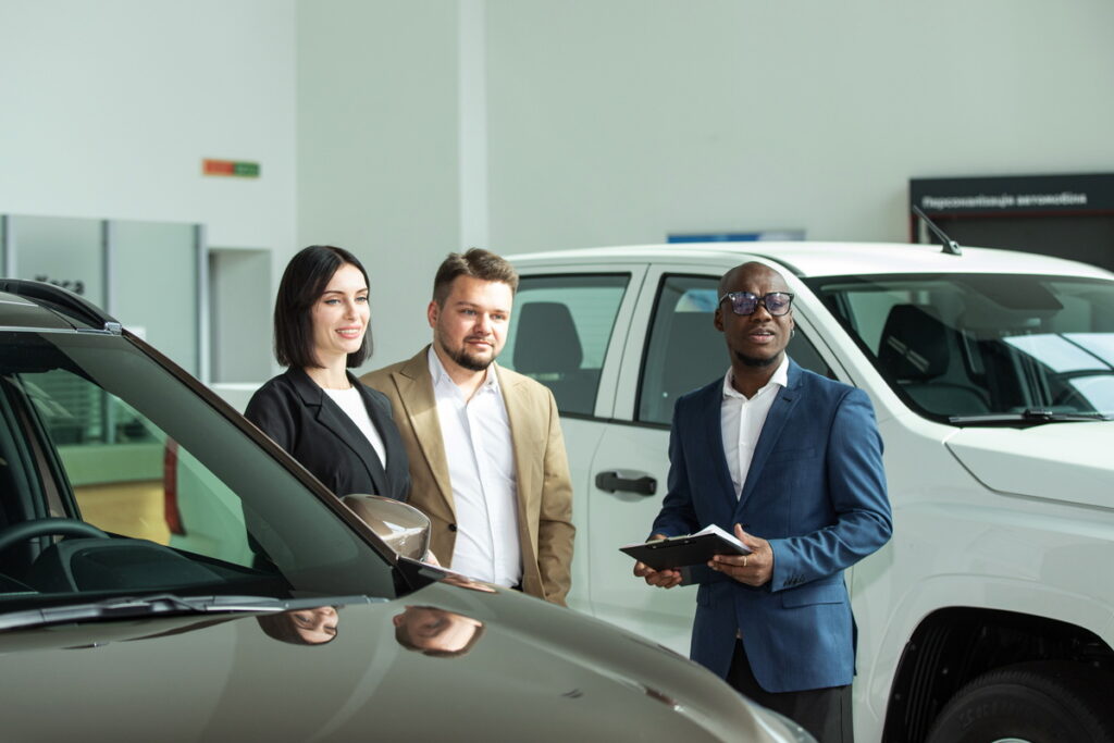 Conseiller automobile expliquant les démarches d'achat d'un véhicule en copropriété à deux acquéreurs dans une concession en 2026.