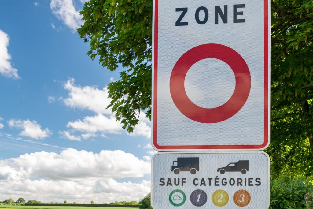 Panneau de signalisation d'une zone à circulation restreinte ZFE indiquant les catégories de vignettes Crit'Air autorisées avec une voiture en mouvement