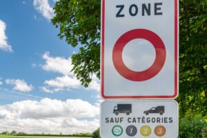 Panneau de signalisation d'une zone à circulation restreinte ZFE indiquant les catégories de vignettes Crit'Air autorisées avec une voiture en mouvement