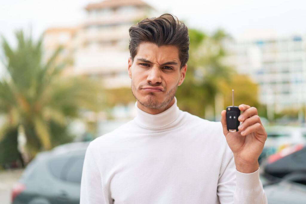 Homme perplexe avec une clé de voiture, bloqué par une erreur sur le certificat de cession