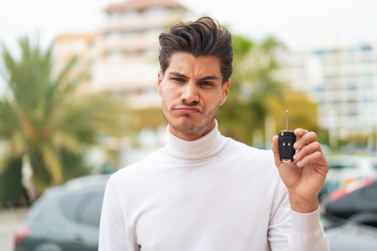 Homme perplexe avec une clé de voiture, bloqué par une erreur sur le certificat de cession