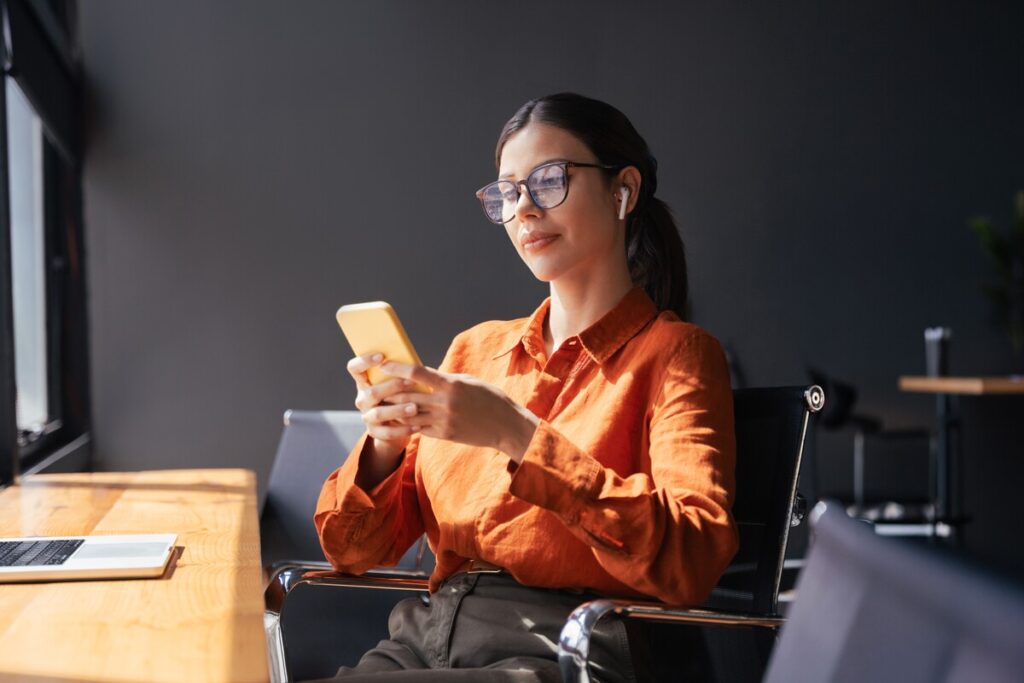 Une femme utilise l'application AMI sur son smartphone pour gérer ses démarches administratives et sa carte grise.