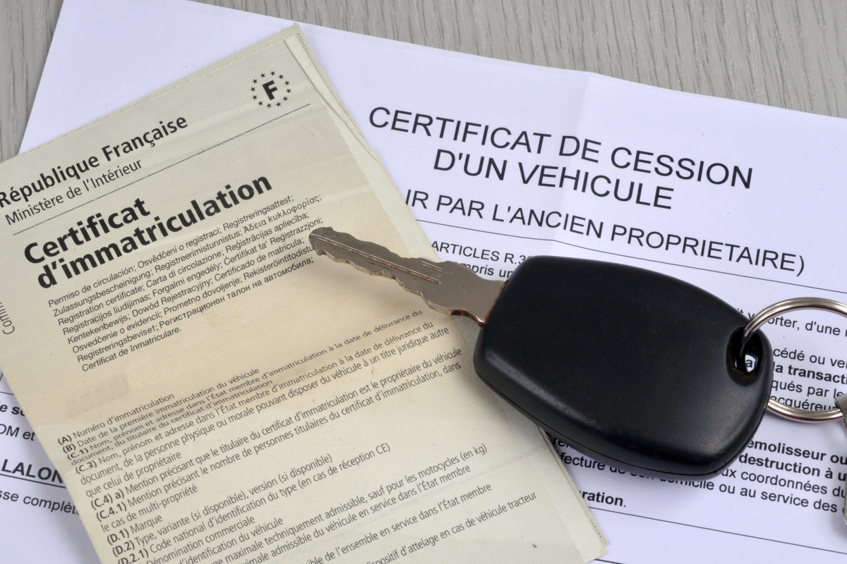 Carte grise barrée et certificat de cession aux côtés de clés de voiture