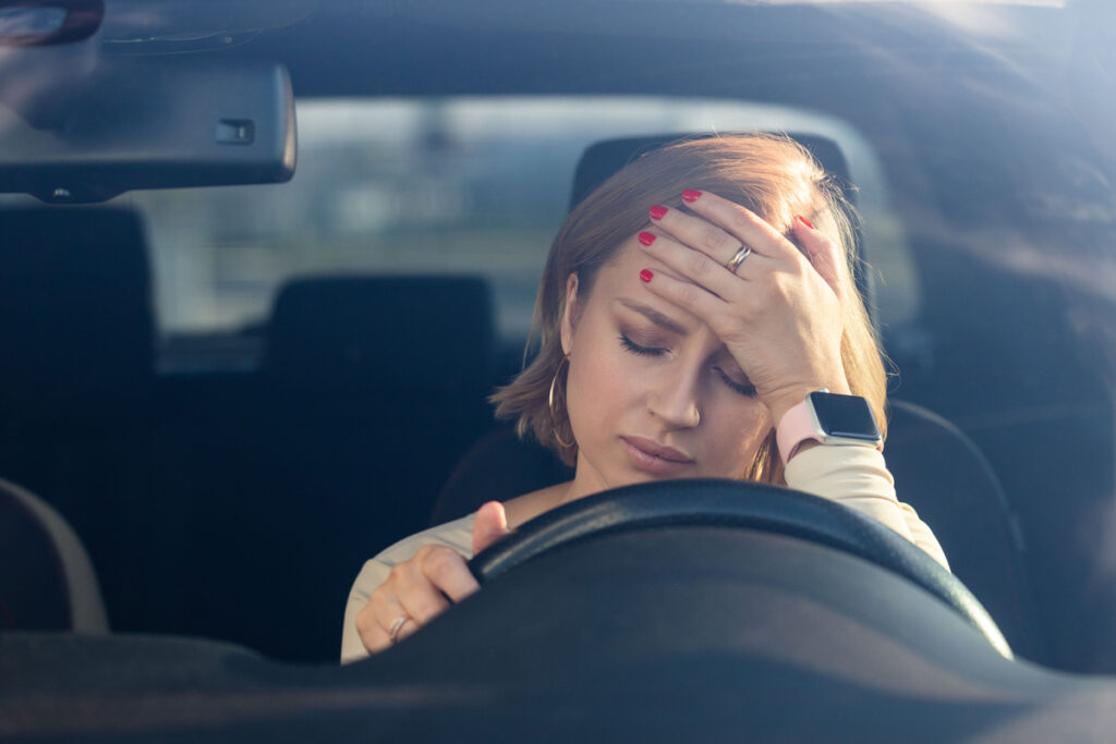 Automobiliste en détresse au volant d'une voiture, paniquée après la perte de sa carte grise à l'étranger.