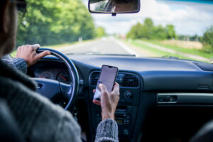Conducteur tenant un téléphone portable en main au volant sur une route